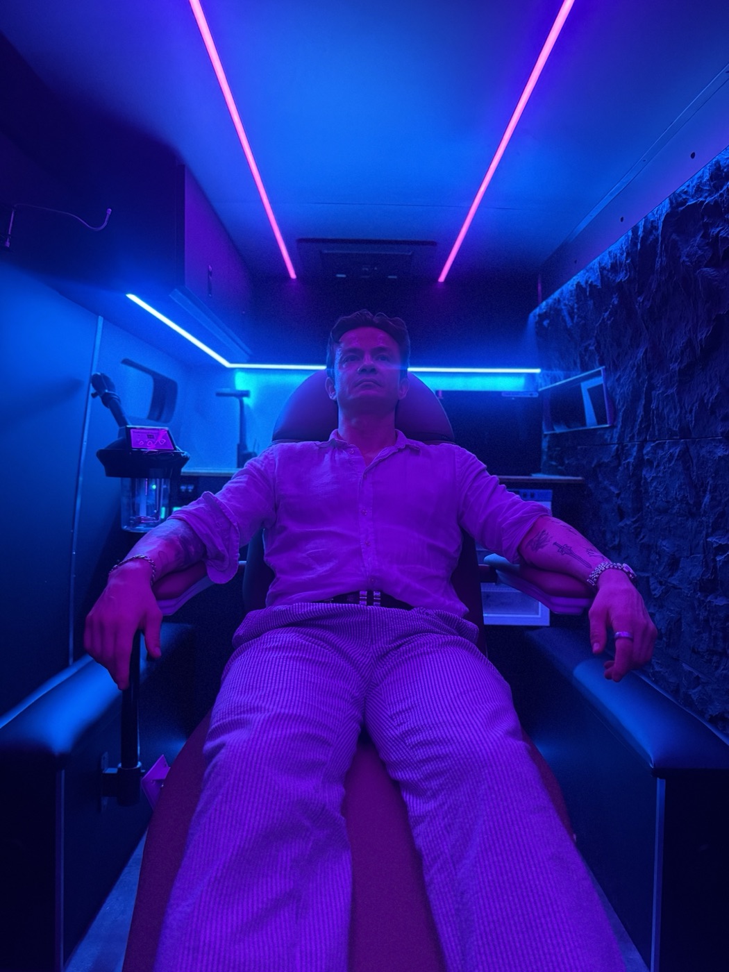 Kevin Hoang seated in the treatment chair under the van's LED lighting